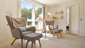 A room with two armchairs, a small table, and a lamp. There are large windows and a door leading to another room. - Nice home in Ringkøbing with WiFi (Ringkøbing)