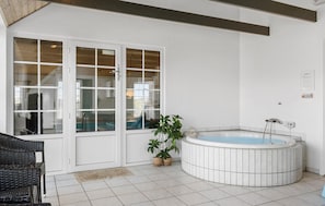 Een badkamer met een bad, een rieten stoel en een potplant.