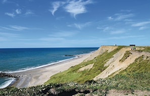 A coastal landscape with a beach, grassy cliffs, and a clear sky. - Gorgeous home in Harboøre with sauna (Harboøre)