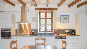 A kitchen with a central island, wooden chairs, a window with a view, and a painting on the wall. - Amazing home in Cravant les Côteaux (Cravant les Côteaux)