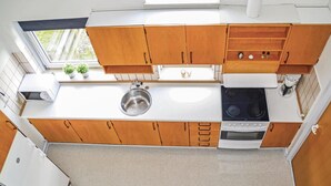 Una cocina compacta con armarios de madera, un lavamanos de acero inoxidable, una estufa y un microondas.