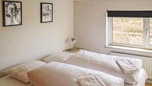Habitación doble con dos camas, una mesita de noche, una lámpara de escritorio y ventana con vistas al campo.