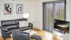 Una sala de estar moderna con un sofá de cuero, una mesa de centro blanca y un televisor de pantalla plana.