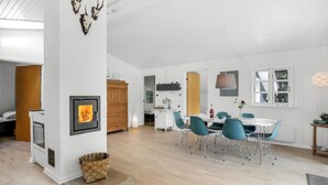 Una cucina moderna con mobili bianchi, piano cottura integrato e zona pranzo con sedie color petrolio e tavolo bianco.