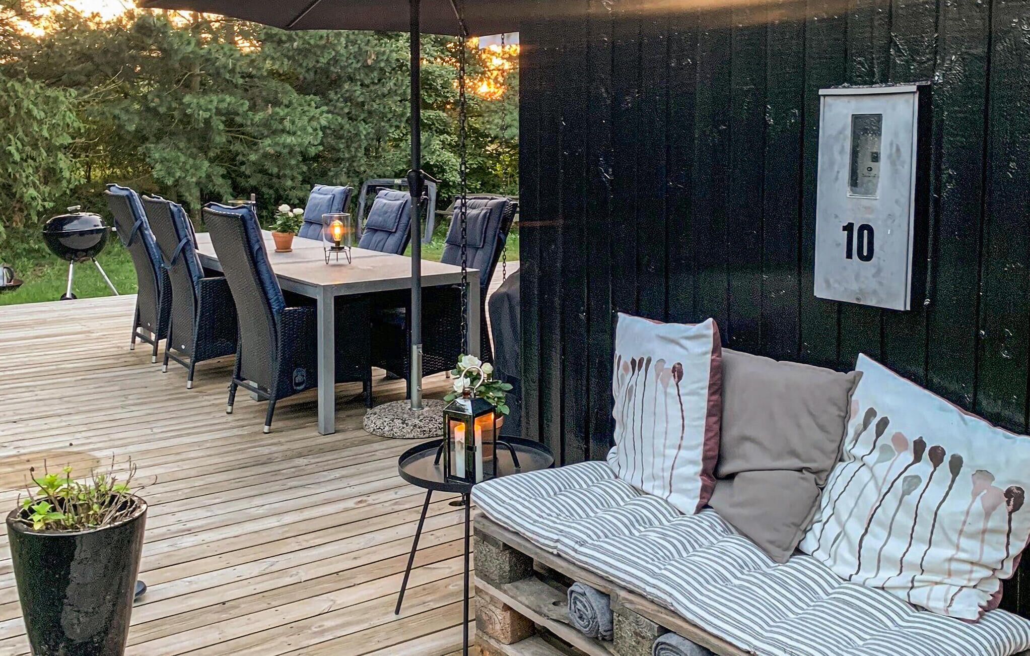 Een terras met tafel en stoelen, een bank en een kleine tuin.