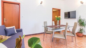 A modern living room with a glass dining table, two sofas, a TV, and a potted plant. - Gorgeous home in Trget (Trget)