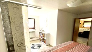 A bedroom with a bed, a bookshelf, and a radiator.