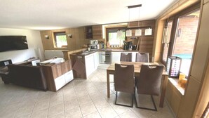 A modern kitchen with a dining area, a built-in oven, and a TV mounted on the wall.