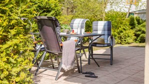 Une terrasse extérieure avec deux chaises en métal, une table et une couverture.