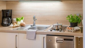 Une cuisine moderne équipée d’un évier en acier inoxydable, d’une machine à café, d’une casserole sur la cuisinière et d’un lave-vaisselle.