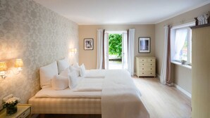 Un dormitorio con cama, lámparas de noche, cómoda y ventana con cortinas.