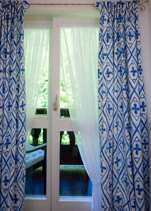 Ein Zimmer mit Fenster, einem Bett und Vorhängen mit geometrischem Muster.
