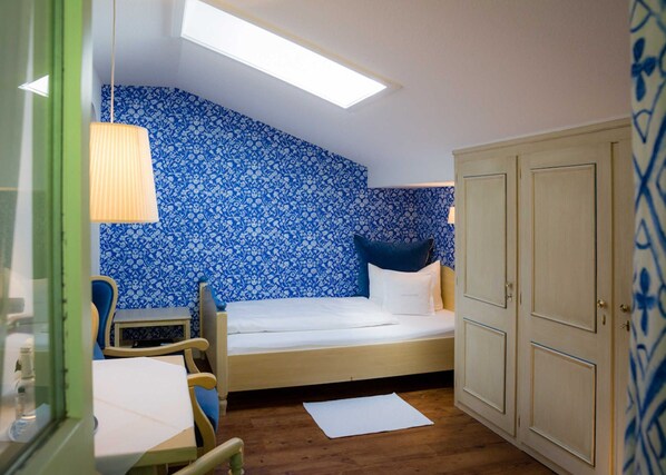 A small room with a bed, a desk, a chair, a wardrobe, and a skylight. - EZ Comfort - Bio Design Boutique Hotel Landhaus St. Georg (Bad Wiessee)