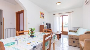 Un comedor con una mesa preparada para dos personas, un televisor y un sofá.