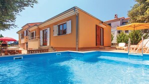 Zona junto a la piscina con piscina, edificio con balcón y mobiliario exterior.