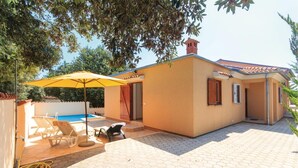 Una casa con piscina, mobiliario de exterior y un patio cubierto.
