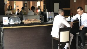 Bar de hotel con mostrador, máquina de café y una mesa de buffet.