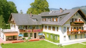 Un edificio ampio su due piani con tetto spiovente, diverse finestre e un prato curato.