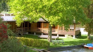 Una baita di legno con una veranda, un piccolo molo e un canale d'acqua.