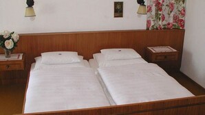 Una cama doble con cabecera de madera, dos mesitas de noche y una cortina estampada con motivos florales.