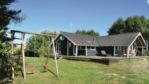 Een houten huis met een veranda, een schommel en een gazon.