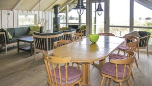 Een eethoek met een houten tafel en stoelen, een groene schaal en een bank met kussens.