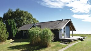 Een klein, laag gebouw met een donker dak en een veranda.