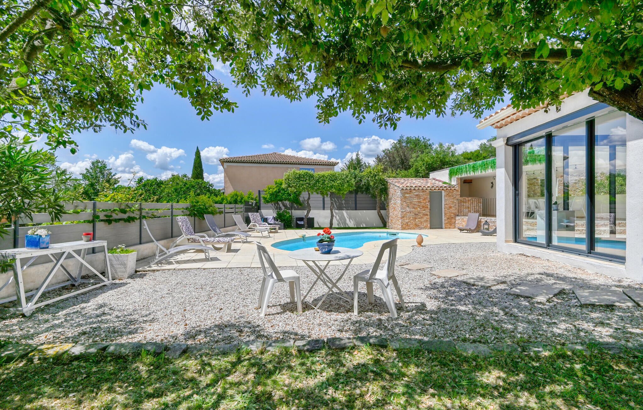 Un jardin avec une piscine, un espace salon extérieur et une vue sur un bâtiment doté d’un toit en tuiles.