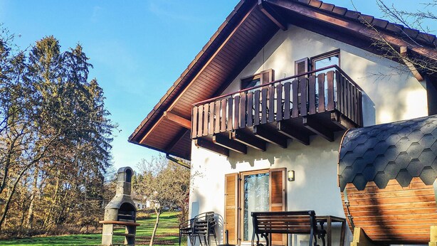 Una casa con balcón, chimenea y antena parabólica.