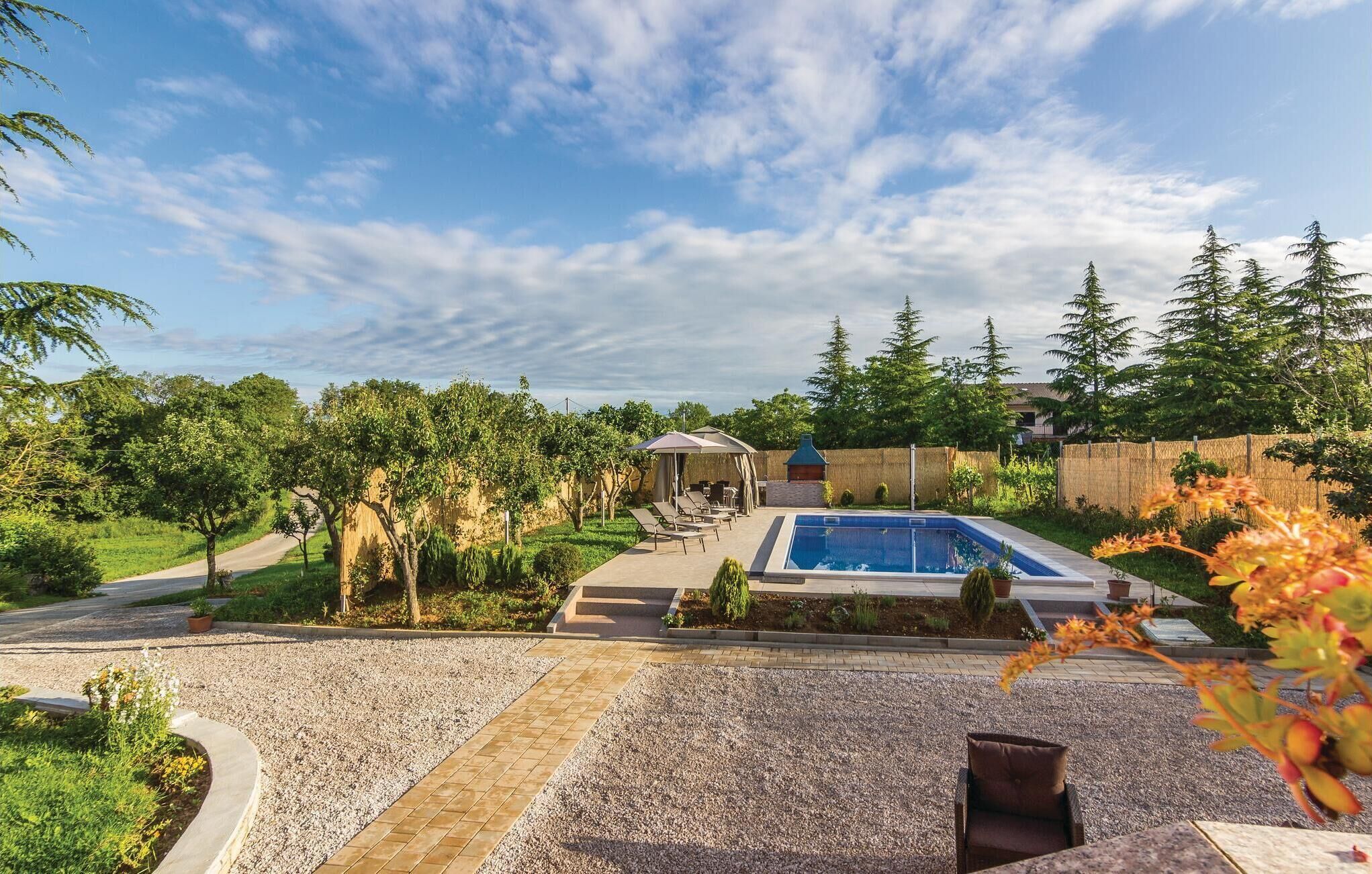 A backyard with a swimming pool, a barbecue area, and a covered seating area.