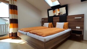 A bedroom with a large bed, a skylight, a TV, and a balcony view.