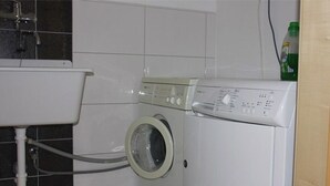 Un espace buanderie compact comprenant un lave-linge, un évier et une bouteille de lessive.