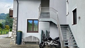 Un bâtiment moderne avec un escalier, un banc et une moto garée à l’extérieur.