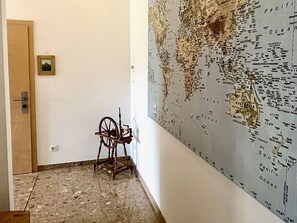 A room with a large world map on the wall, a wooden chair, and a door.