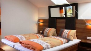 Un lit double avec une tête de lit en bois, deux tables de chevet et une fenêtre avec des rideaux.