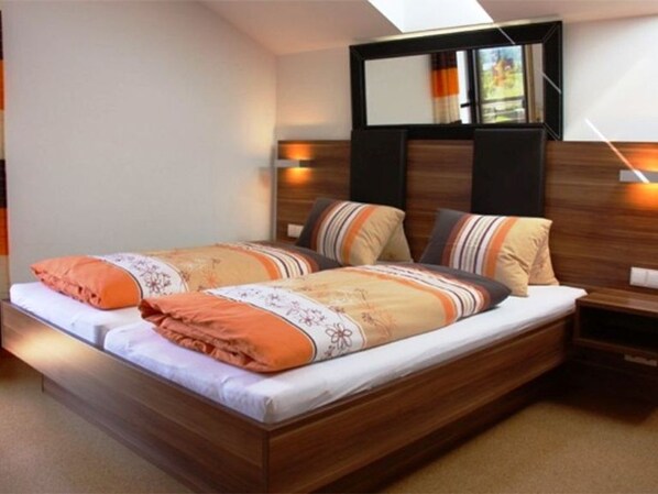 A double bed with a wooden headboard, two bedside tables, and a window with curtains.