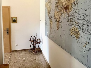 Une pièce avec une grande carte du monde accrochée au mur, une chaise en bois et une porte.