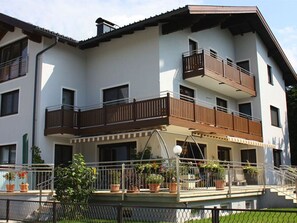 A multi-story building with balconies, a covered outdoor area with potted plants, and a visible staircase.
