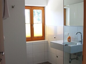 A bathroom with a window, a sink, and a mirror.