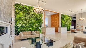 A modern living room with a glass coffee table, beige sofas, a fireplace, and a green vertical garden wall. - Garden Suite Penthouse (Prora/Rügen)