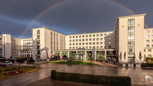 A hotel with multiple floors, a central courtyard, and outdoor seating areas. - Garden Suite Penthouse (Prora/Rügen)