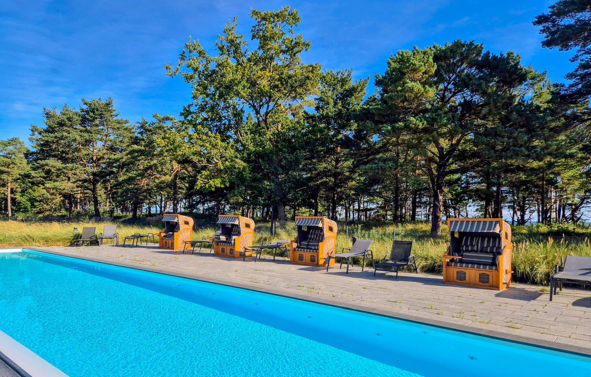 A swimming pool with lounge chairs and a fence.