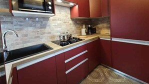 A compact kitchen with a built-in microwave, a gas stove, and a coffee maker.