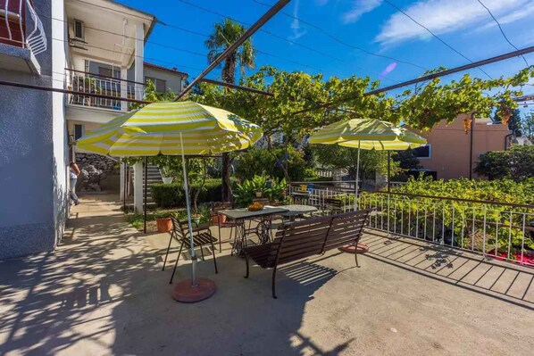 An outdoor patio area with tables, chairs, and striped umbrellas.