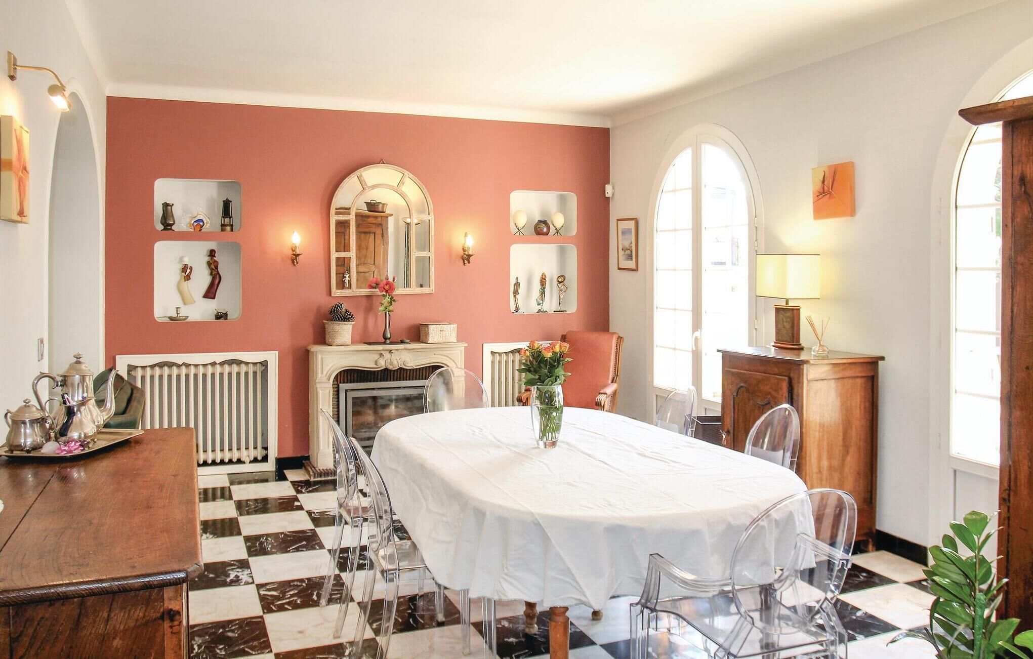 Ein Esszimmer mit Schachbrettboden, einem weißen Tisch und klaren Stühlen.