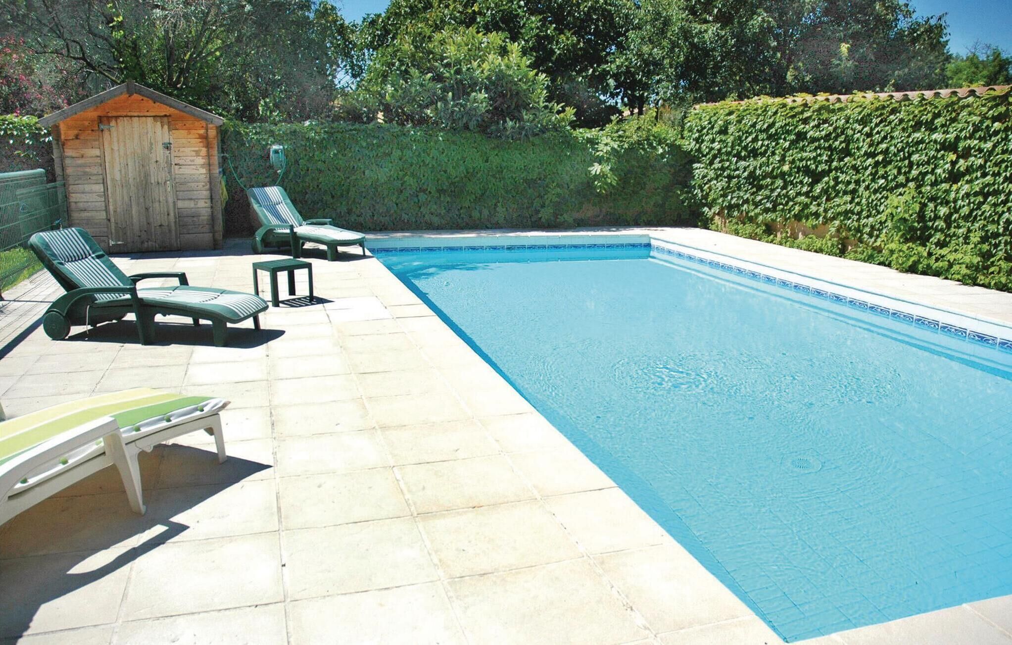 Ein Schwimmbecken mit Liegestühlen und einer kleinen Gartenhütte.