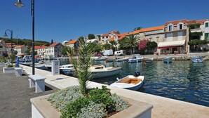 A marina with boats docked, a stone building with a red roof, and a street with shops and cafes. - 2 bedroom amazing apartment in Selca (Selca)
