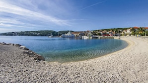 A pebbled beach with clear water, a dock with boats, and buildings in the background. - 2 bedroom amazing apartment in Selca (Selca)