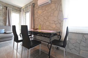 A dining area with a stone wall, a table with chairs, and a window with curtains.