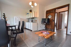 A modern kitchen with white cabinets, a microwave, and a television on a wooden stand. - Holiday apartment mit Balkon (Gabonjin)